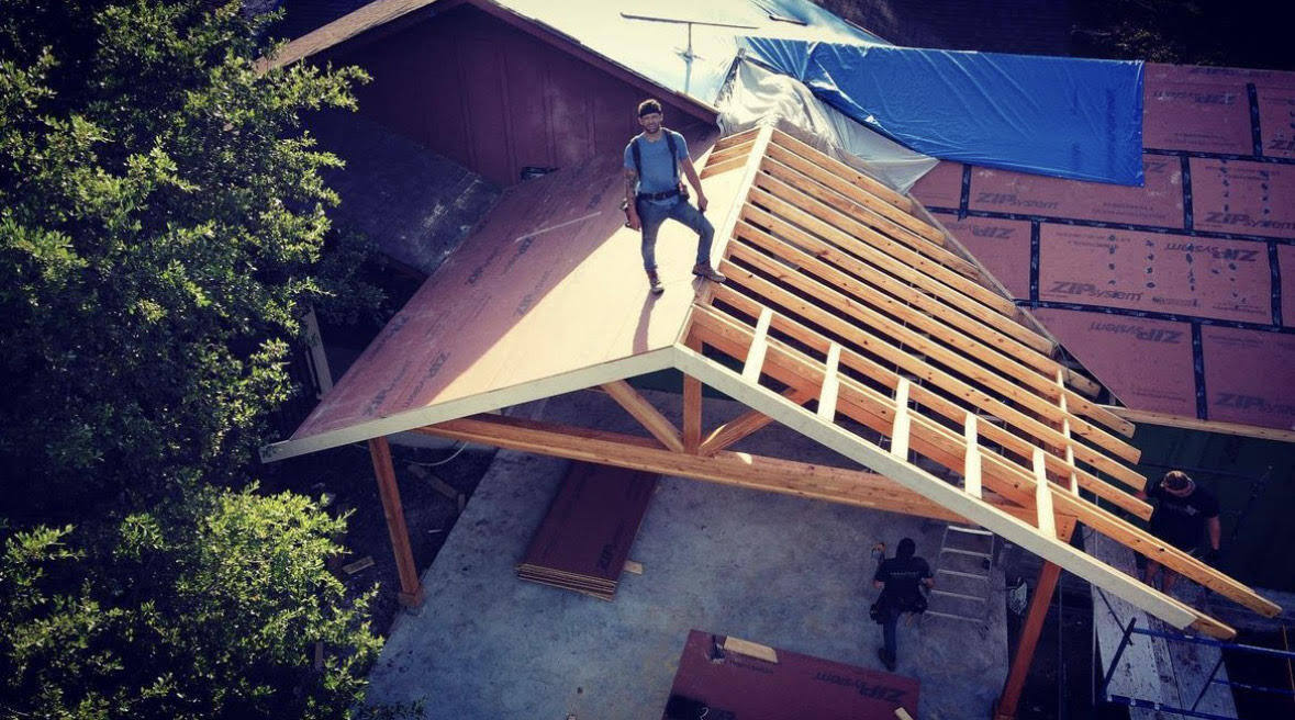 A photo of Joe Waller standing on a roof top that is being built, you can see zip sheeting and exposed rafters.